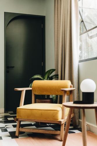 a yellow chair in front of a door with a plant at Casa Ixaya by Barrio México in Guadalajara