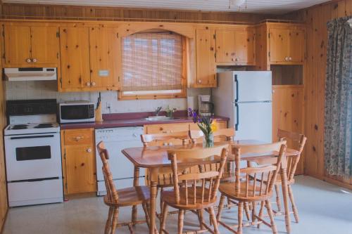 a kitchen with a table and chairs and a refrigerator at Hidden Acres Cottages in Cavendish