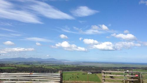 a pasture with a fence and a blue sky with clouds at Aashay Country Stay in Fish Creek