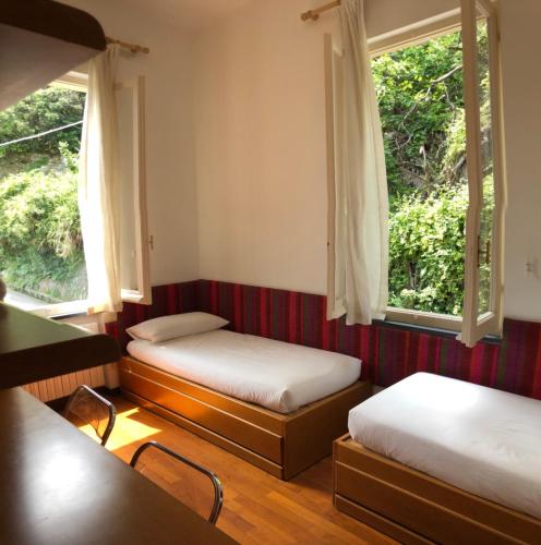 twee bedden in een kamer met twee ramen bij Large Apartment (3 bedrooms - 2 bathrooms), 50 meters from the beach in Paraggi
