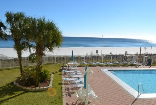 a swimming pool with chairs and umbrellas next to the beach at Sunswept 203 Condo in Orange Beach