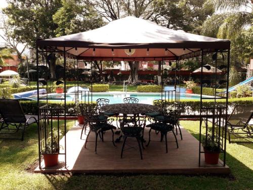 a gazebo with tables and chairs next to a pool at Villa Paraiso in Emiliano Zapata