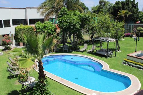 a swimming pool in a yard with a palm tree at Hotel Boutique La Rioja in Atlixco