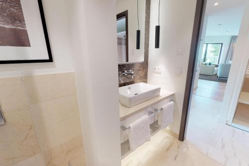 ein weißes Badezimmer mit Waschbecken und Spiegel in der Unterkunft White Pearl Apartment 3.12 in Timmendorfer Strand