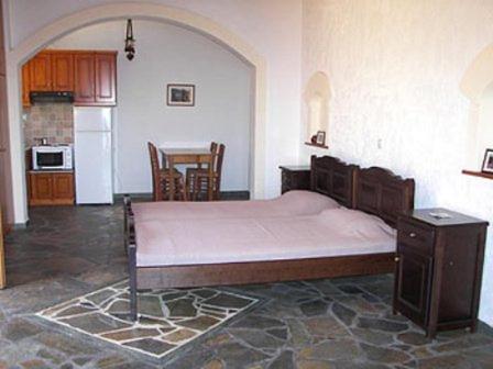 a bedroom with a large bed and a kitchen at Niriides Studios in Armenistis