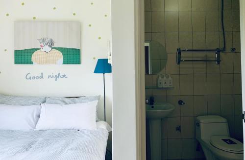 a bedroom with a bed and a bathroom with a toilet at Puli Islet Inn in Puli