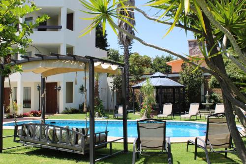 een zwembad voor een villa met stoelen en een parasol bij Hotel Boutique La Rioja in Atlixco