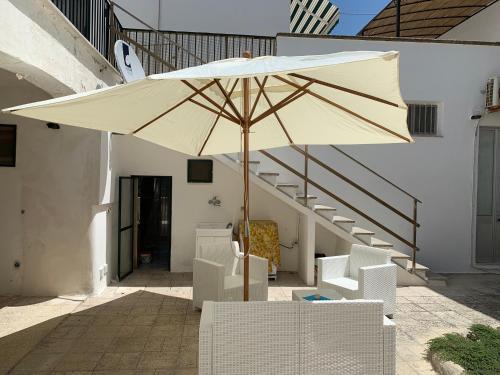 um grande guarda-chuva branco sentado ao lado de cadeiras e escadas em Villa Azzurra Sct em Santa Cesarea Terme