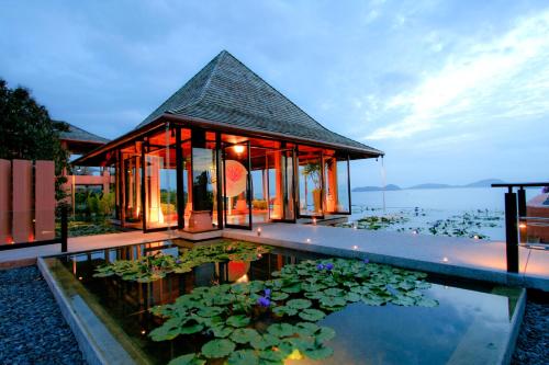 a villa with a pond in front of a house at Sri Panwa Phuket Luxury Pool Villa Hotel - SHA Plus in Panwa Beach