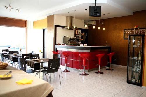a restaurant with a bar with red chairs and tables at Tea Palace Hotel in Casapulla