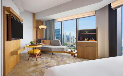 a hotel room with a bed and a couch and a tv at Andaz Singapore, By Hyatt in Singapore