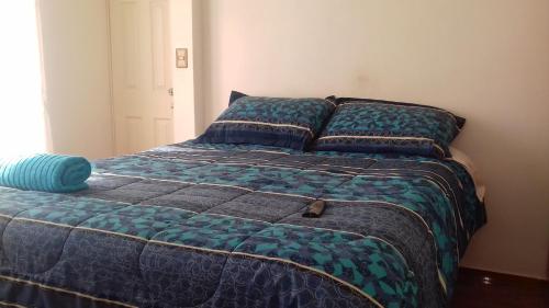 een bed met een blauw dekbed in een slaapkamer bij Casa Blanca Hospedaje in Mejillones