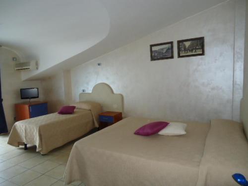 um quarto de hotel com duas camas e uma televisão em Tea Palace Hotel em Casapulla