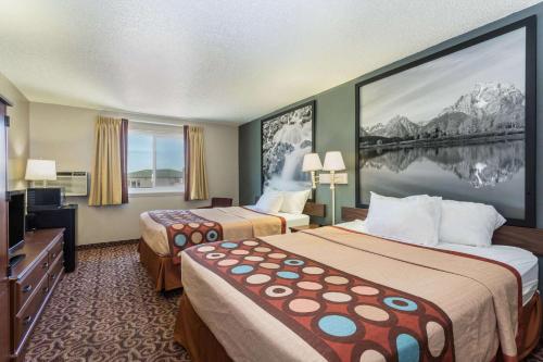 a hotel room with two beds and a flat screen tv at Super 8 by Wyndham Gillette in Gillette