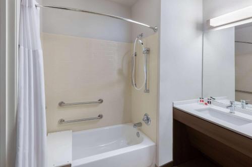 y baño con bañera, lavamanos y ducha. en Microtel Inn & Suites by Wyndham College Station, en College Station