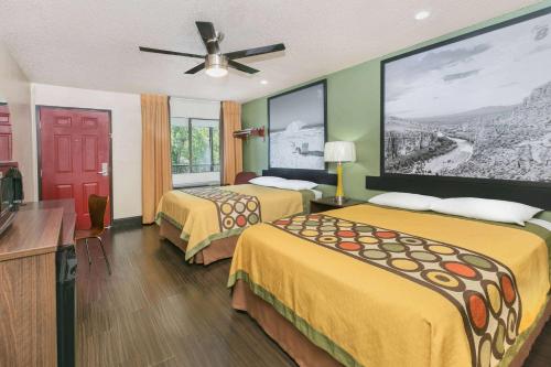 a hotel room with two beds and a flat screen tv at Super 8 by Wyndham Austin University/Downtown Area in Austin