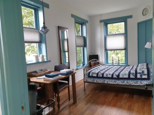 a bedroom with a bed and a desk and windows at Hunsingo Texel in De Cocksdorp