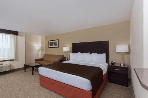 a hotel room with a large bed and a chair at AmericInn by Wyndham Janesville in Janesville