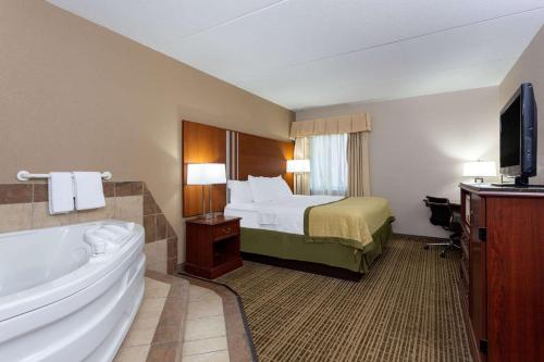 a hotel room with a bed and a tub and a television at Baymont by Wyndham Elkhart in Elkhart