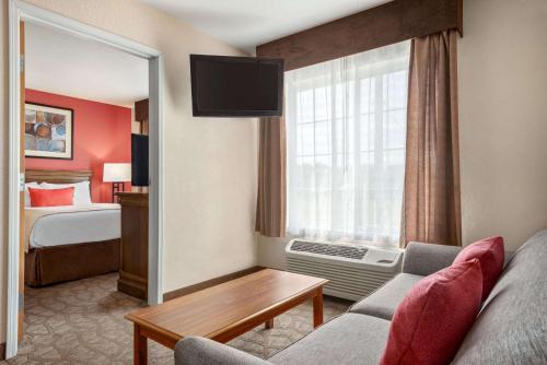 a hotel room with a couch and a bedroom at Hawthorn Suites by Wyndham Decatur in Decatur