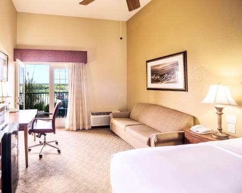 a hotel room with a couch and a table and a desk at La Quinta by Wyndham Marble Falls in Marble Falls