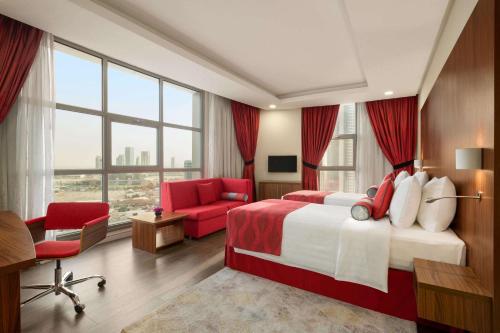 a hotel room with a large bed and a red chair at Ramada Encore by Wyndham Kuwait Downtown in Kuwait