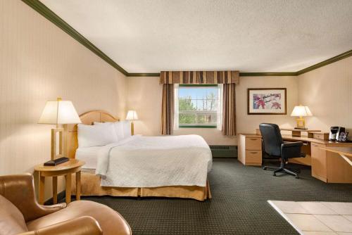 Habitación de hotel con cama y escritorio en Travelodge by Wyndham Dawson Creek en Dawson Creek