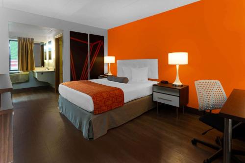 a hotel room with a bed with an orange wall at Howard Johnson by Wyndham Waukegan Great Lakes in Waukegan