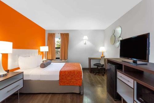 a hotel room with a bed and a flat screen tv at Howard Johnson by Wyndham Waukegan Great Lakes in Waukegan