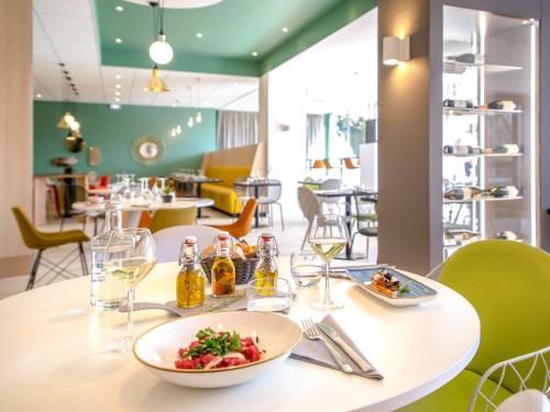 a table with a plate of food and wine glasses at Mercure Cavaillon in Cavaillon