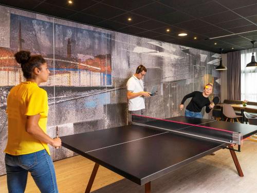 a group of people standing around a ping pong table at ibis Le Havre Centre in Le Havre
