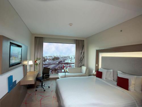 a hotel room with a large bed and a window at Novotel Ahmedabad in Ahmedabad