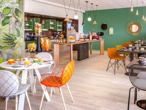 a restaurant with tables and chairs and a green wall at Mercure Cavaillon in Cavaillon