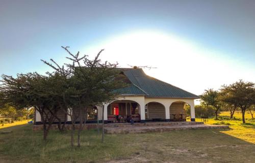 a white building with a green roof in a field at Narasha Homestay - Maasai Mara in Talek