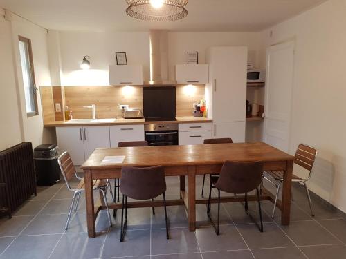 une cuisine avec une table et des chaises en bois dans l'établissement La maison des bateaux, à Saint-Valery-sur-Somme