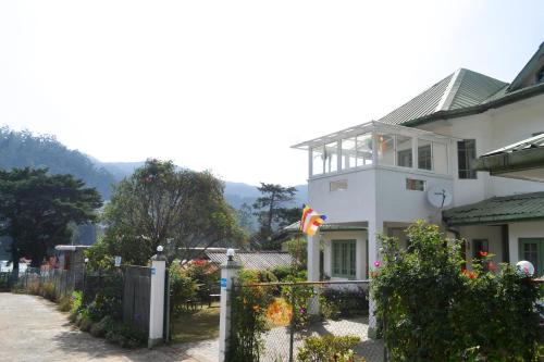 a white house with a fence in front of it at Samri Holiday Bunglow in Nuwara Eliya