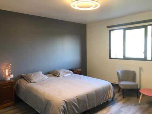 a bedroom with a bed and a chair and a window at Le domaine de la carperie in Bréhal