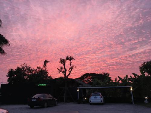 a pink sky with cars parked in a parking lot at Alinda Resort in Phetchaburi