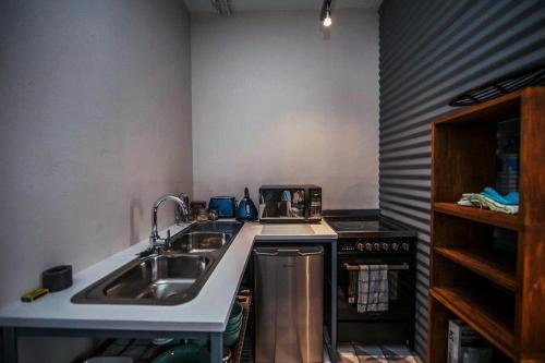 a small kitchen with a sink and a stove at Cozy, Modern Living in Maboneng: Artison Lofts 105 in Johannesburg