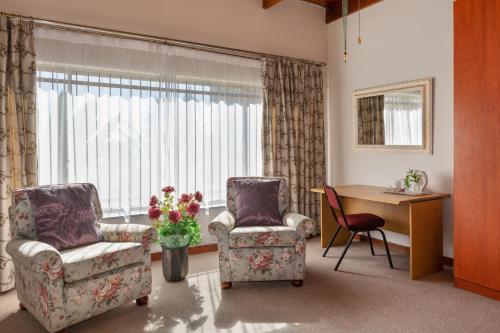 a living room with two chairs and a desk and a window at Aberfeldy Bed & Breakfast in Midrand