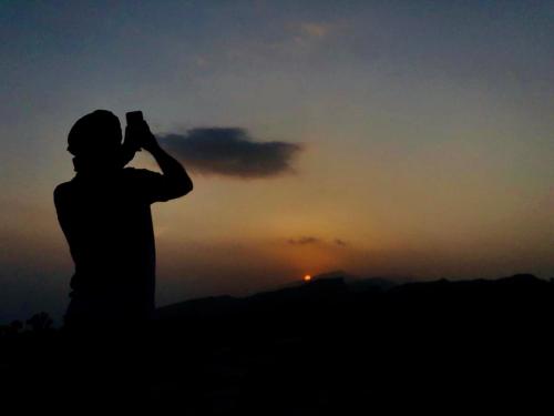 a person taking a picture of the sunset at Hissen Al-Misfah in Misfāh