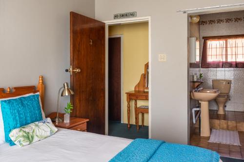 a bedroom with a bed and a bathroom with a sink at Aberfeldy Bed & Breakfast in Midrand