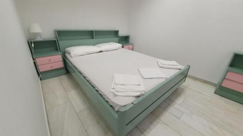 a bedroom with a green bed with two night stands at TK-George Apartments by the Airport in Markopoulo
