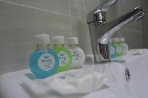 Tres botellas de crema hidratante están sentadas en el lavabo del baño. en Orient Star Hotel, en Tashkent