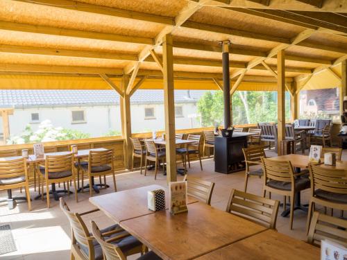 um restaurante com mesas e cadeiras de madeira e um pátio em Camping De Grienduil em Nieuwland