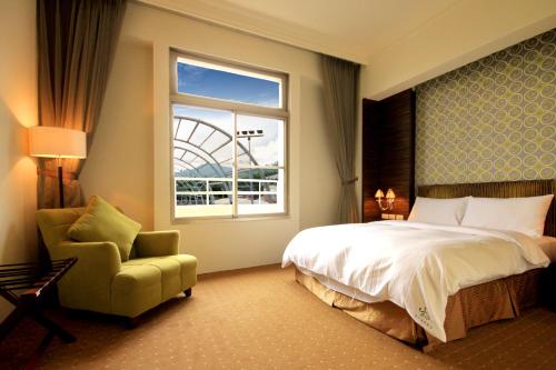 a bedroom with a bed and a chair and a window at Mountain Fish Water Hotel in Jiji