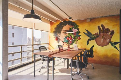 een muurschildering in een kantoor met een tafel en stoelen bij Selina Miraflores Lima in Lima