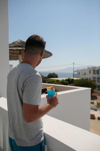a man standing on a balcony holding a cup at Iades Studios & Apartments in Agia Anna Naxos