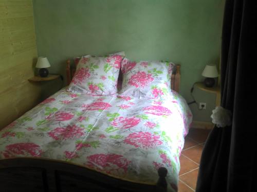 a bed with a pink and white comforter and two lamps at Gîte Le Pont du Monet in Usson-en-Forez