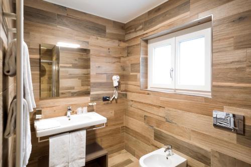 a bathroom with wooden walls and a sink and a window at Hotel Baia di Paré in Valmadrera